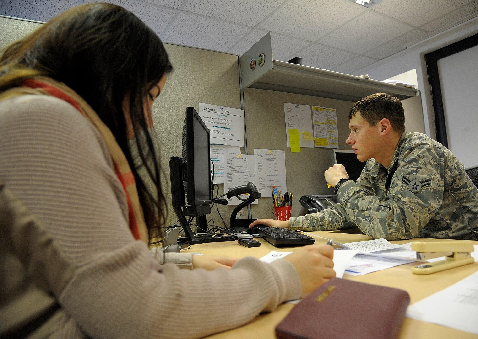 Administrative specialist reviewing applicant enlistment paperwork and entering data into secure personnel systems at a Navy recruiting support office